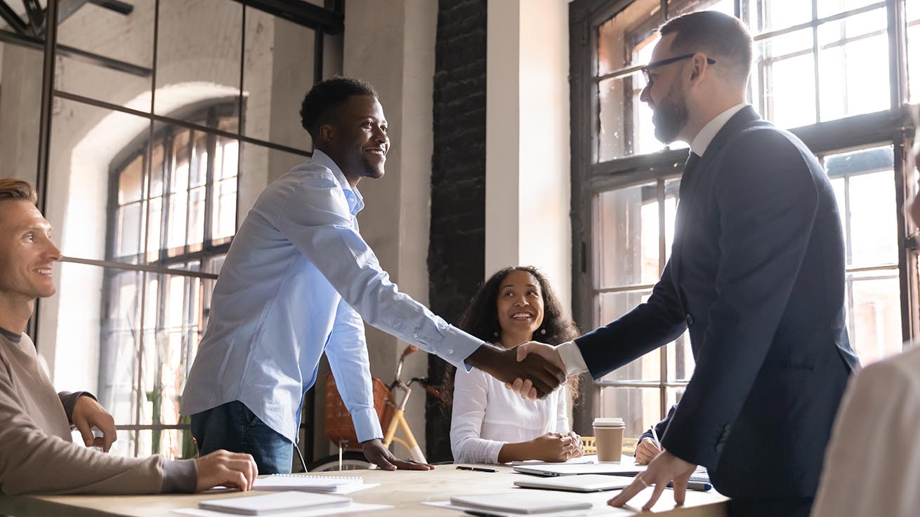 Happy diverse business partners handshaking at group negotiation